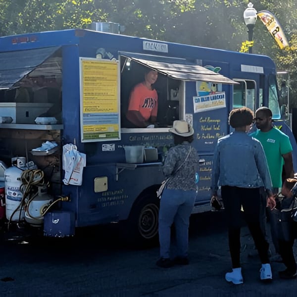 A blue Da Blue Lagoon food truck with a person serving customers from the window.