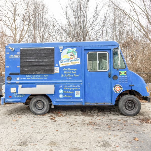 Da Blue Lagoon Jamaican Kitchen food truck, a vibrant blue vehicle with a Jamaican flag and palm tree logo.