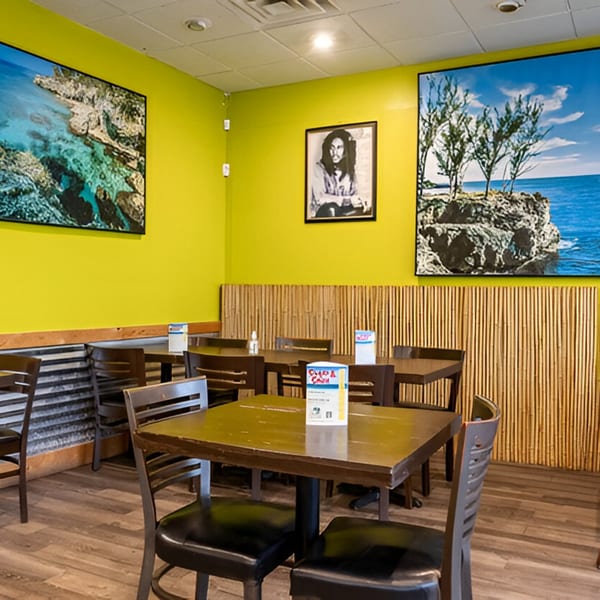 Interior of Da Blue Lagoon, a Jamaican restaurant, with lime green walls, Bob Marley art, and wooden tables.