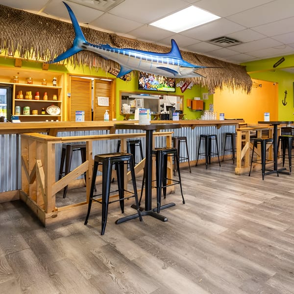 Interior of Da Blue Lagoon Jamaican Kitchen with a blue marlin decoration, bar seating, and lime green walls.