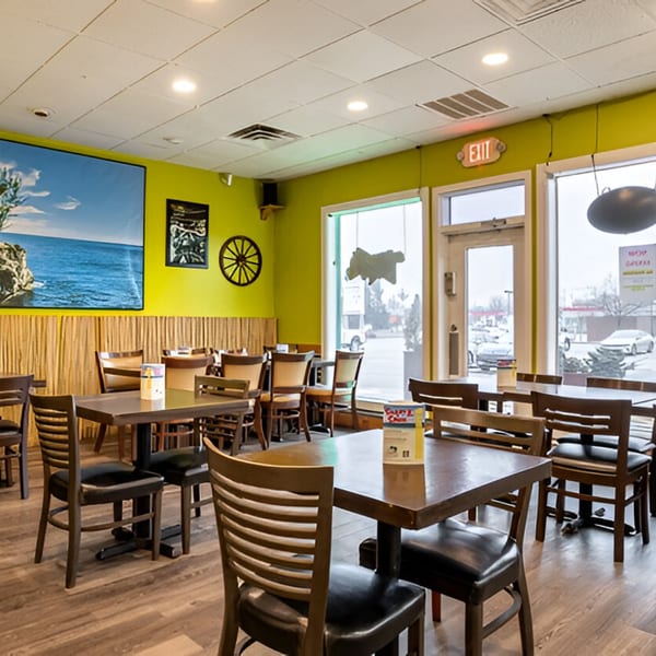 Interior of Da Blue Lagoon Jamaican Kitchen, featuring lime green walls, wooden tables, and chairs.