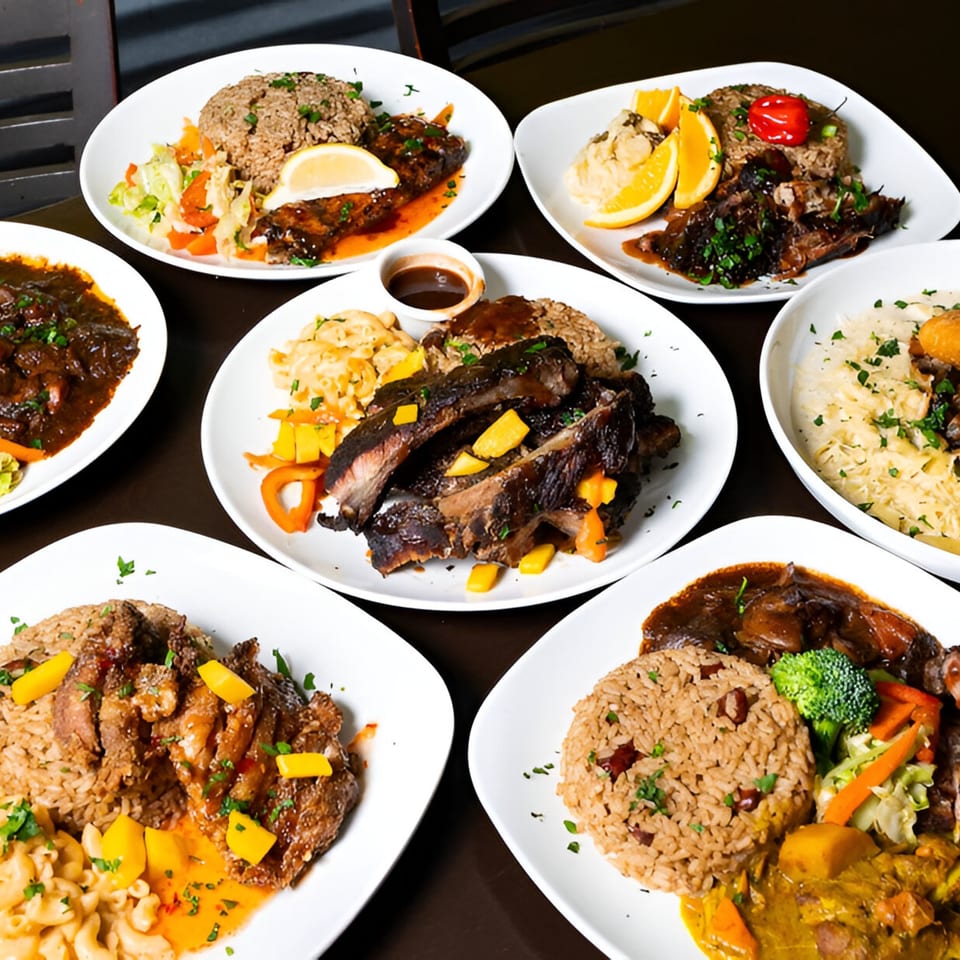 A table filled with various Jamaican dishes, including ribs, rice, and mac and cheese.