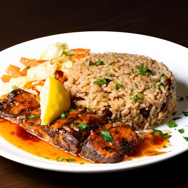 Jamaican brown stew fish with rice and peas, steamed vegetables, and a lemon wedge.
